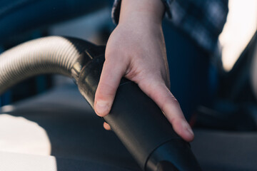 White young hand cleaning car with vacuum cleaner