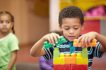 The building blocks of my future. An interested pre-school child building something with plastic blocks.