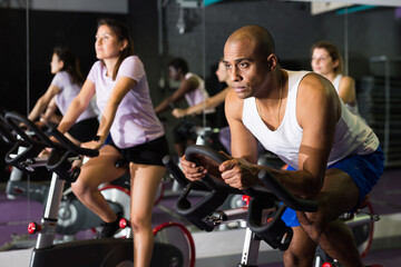 Portrait of sporty man training on stationary bike in gym