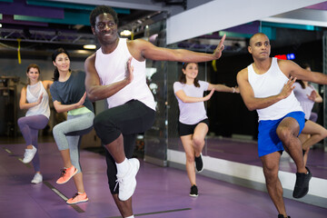 Group of active people practicing together in gym