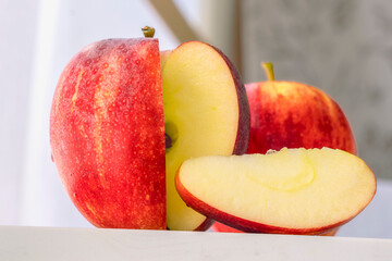 a red ripe juicy apple with a slice cut out of it and several apples in a blur on the background the concept of a healthy diet