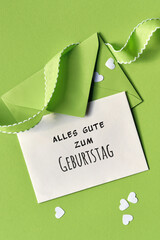Alles gute zum Geburtstag means Happy Birthday text on card. Spring background in green. Paper...