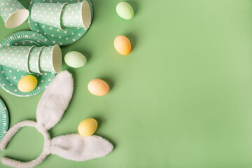 Easter table. flat lay. eggs and paper plates and glasses on a green background