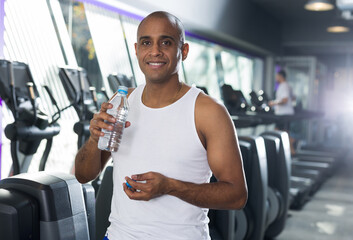 Positive man with bottle of water in a sports club
