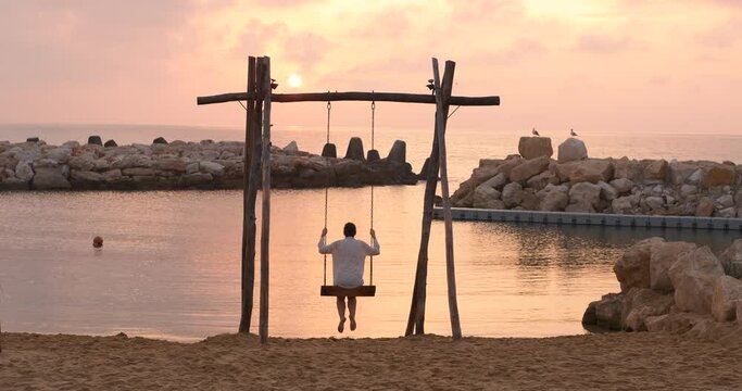 Summer resort on swing. A woman pas her summer time on the wooden swing on the beach.