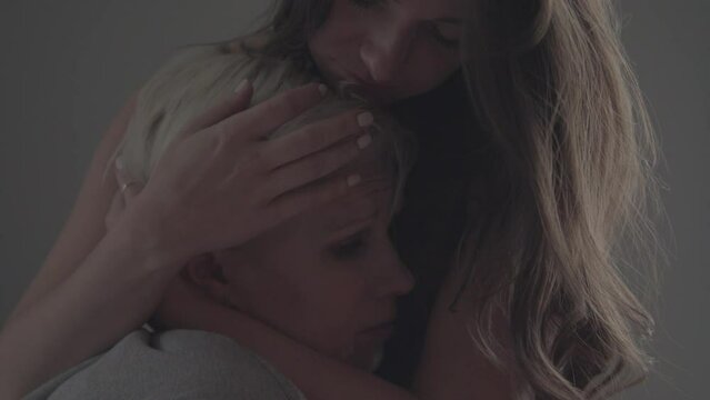 Emotional scene of lesbian couple hugging, a stunning blonde with short hair and a beautiful brunette with long hair share a touching moment