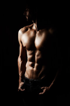 Sculpted to perfection. Low-key image of a muscular young man on a black background.