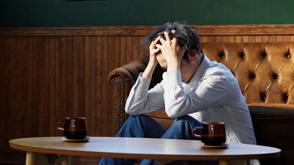 部屋で一人で落ち込んでいる男性