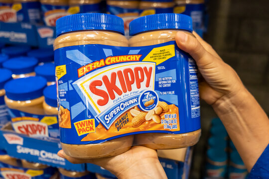 Los Angeles, CA/USA 08/09/2021 Shoppers hand holding a Twin Pack Plastic Jars of Skippy brand peanut butter in a supermarket aisle