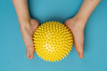 children's feet with a yellow balancer on a light blue background, treatment and prevention of flat...