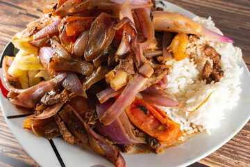 Lomo saltado with beef and Italian tripe with white rice, julienned onions, tomatoes and golden French fries