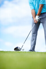 Fototapeta premium Grounding the club. Cropped image of a young male golfer teeing up to play a shot with his driver.