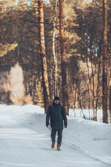 A man with a tourist fabric backpack, in a winter forest, in a jacket and orange trekking boots outdoors