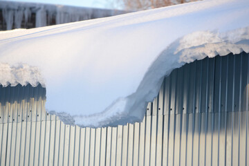 A roof of a structure with snow hanging from it