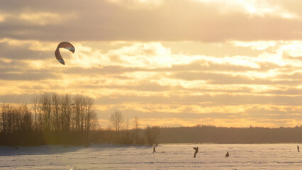 snowkiting on a frozen lake at sunset