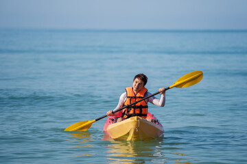 man in life jacket paddling a kayak boat in sea
