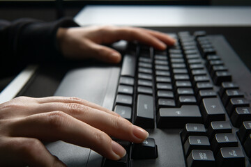Close up image of woman hands typing on computer keyboard and surfing the internet on table.