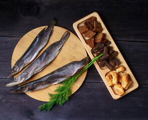 Sun dried fish, salted smelts over wooden background, top view, copy space. Snack for beer dried smelts.