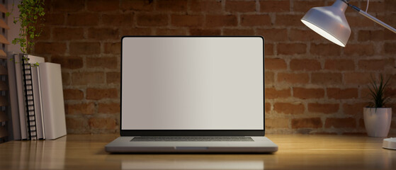 A notebook laptop computer mockup on wooden table over red brick wall
