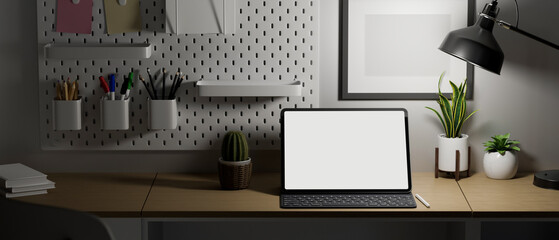 Modern home office desk at night, portable tablet mockup on table under lights