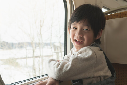 Happy asian child traveling on train looking from the window.