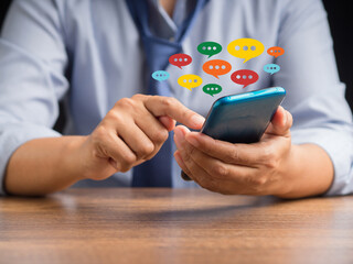 Close-up of hands using mobile phone with colorful chat icons on the application