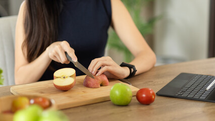 Obraz na płótnie Canvas A woman chopping red apple on wooden cutting board