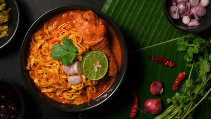 Top view, Khao Soi Kai bowl over green banana leaf background
