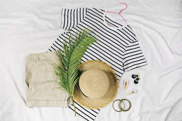 Straw hat, t shirt, shorts, sandals on white background. Trendy summer outfit. Flat lay with...