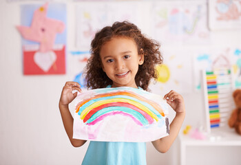 Dont you just love the colors. Shot of a little girl holding up a picture she painted of a rainbow.