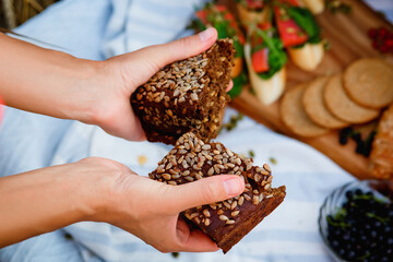 A woman breaks grain black bread at a picnic in nature. Selective focus.