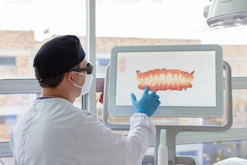 Male dentist analyzing a virtual model of a female patient