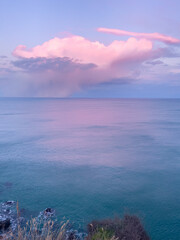 A large thundercloud on the horizon over the sea. 