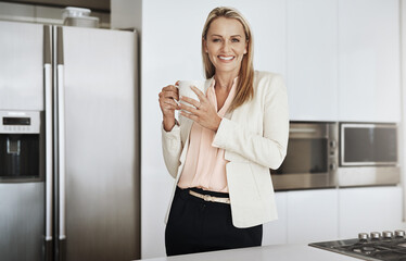 Got to keep on the go. Portrait of a cheerful middle aged businesswoman standing behind a counter while drinking a cup of coffee inside of a kitchen during the day.