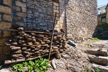dung fuel for heating lies against a stone wall