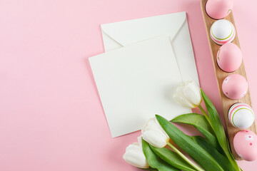 Easter background with easter eggs, white tulips and empty card for text. Top view, flat lay