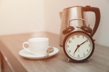 Morning Time with bell clock and Coffee or Tea hot drinks on wooden table.