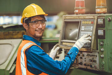 Portrait Happy Asian worker operate CNC machine in heavy steel industry factory. staff smiling with mechanical control panel.