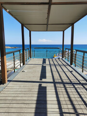 Observation deck over Fig Tree Bay beach overlooking an island in the Mediterranean Sea and a blue sky with clouds.