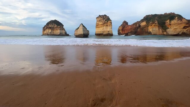Waves crashing on shoreline with rock formations reflected, reframe high, The Great Ocean Road in Victoria, Australia