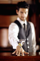 For you. Portrait of a handsome young bartender mixing a cocktail for a customer.