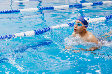 latin young man swimmer athlete wearing cap and goggles in a swimming training holding On Starting...