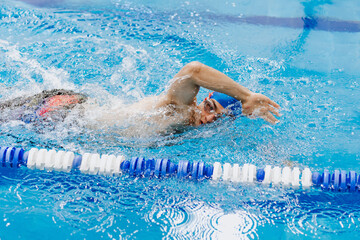 latin young man swimmer athlete wearing cap and goggles in a swimming training holding On Starting...