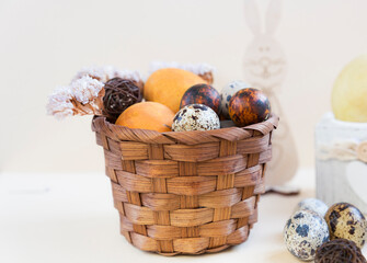 Fototapeta na wymiar Rattan basket with Easter eggs on a light background. Easter background. Decorations Easter bunny, quail eggs. Close-up. Selective focus