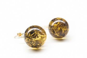 Handmade lichen earrings closeup. Jewelry making hobby. Natural plants inside epoxy rsin sphere balls. Selective focus on the details, object isolated on white background.
