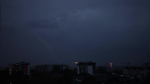 Lightning bolts flashes composition with view of night city sky with clouds. Thunderstorms, lightning over the night city. Low key lighting. Underexposed. Pink light