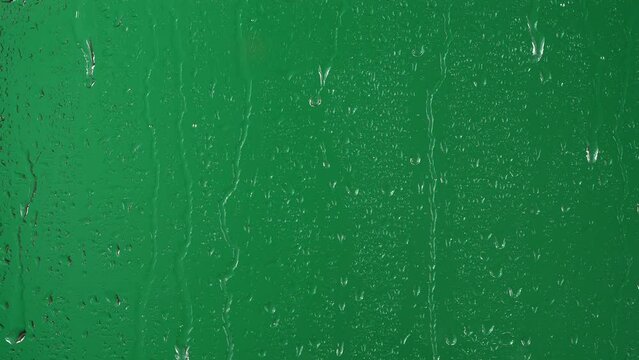 Water rainfall, rain drops falling on window glass over chroma key green screen