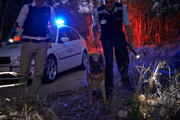 We found it. Shot of two policemen and their canine tracking a suspect through the brush at night. © Yuri Arcurs/peopleimages.com