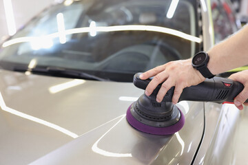 Male hands are polishing the hood of a vehicle