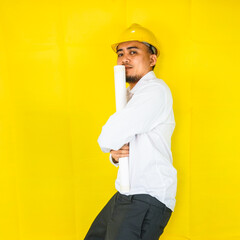 A young Asian civil engineer in a hard hat is standing on a yellow background. Act like a builder and real estate engineer.